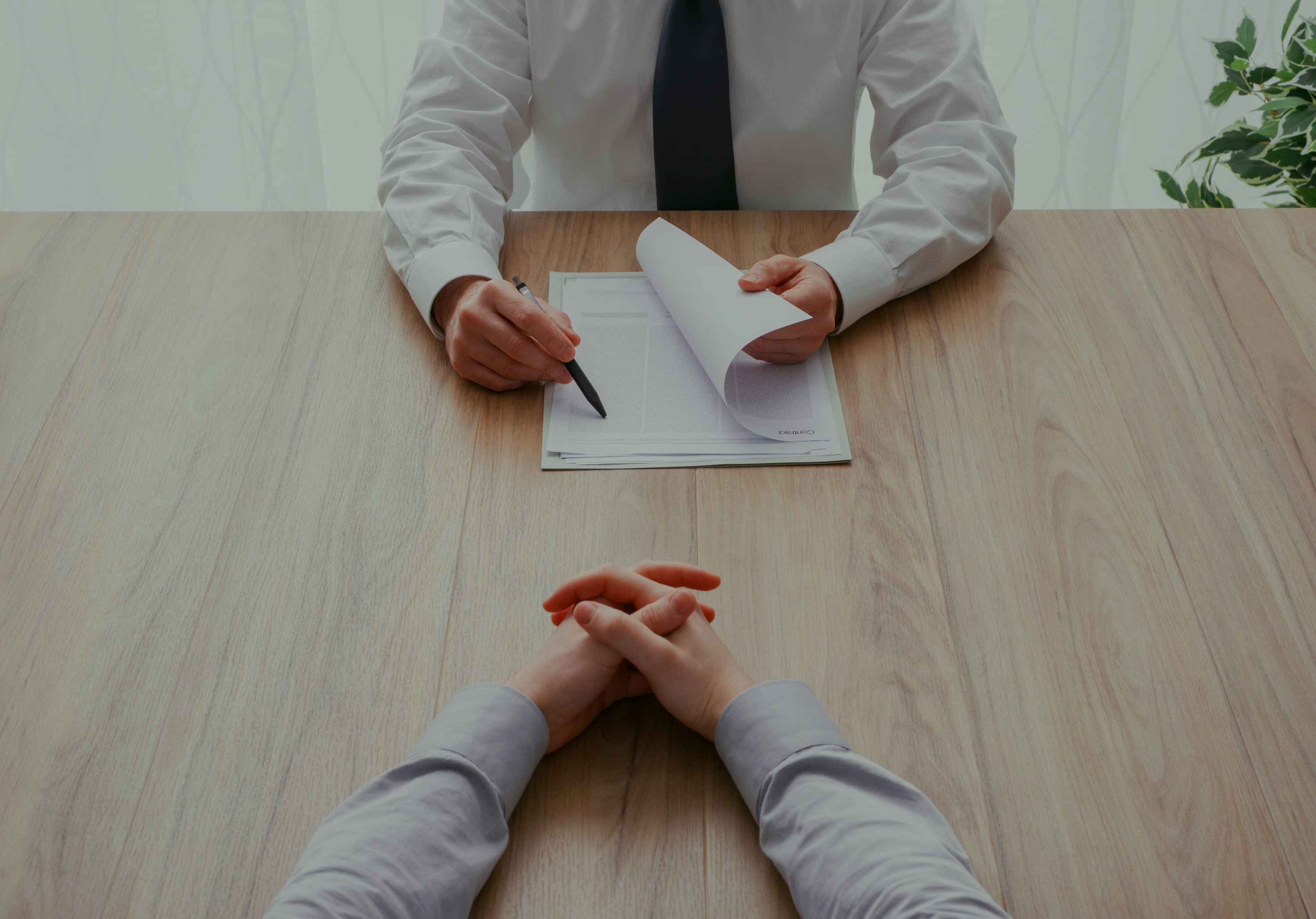 Two business professionals collaborating at a table, one transcribing the conversation.